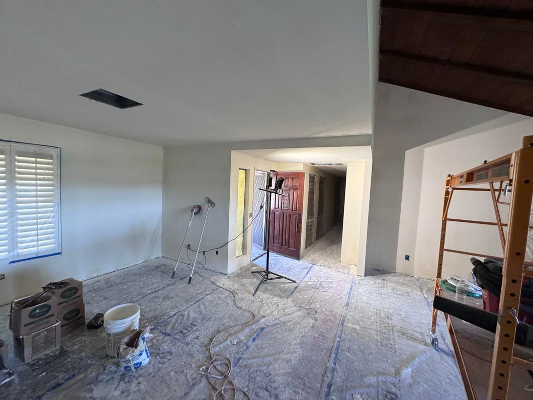 Renovated room with drywall dust, ladder, tools, and open doorway into a hallway