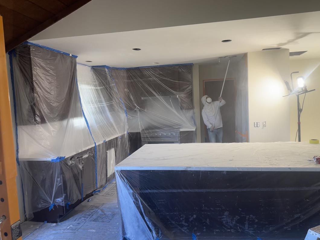 Room being painted or renovated, with plastic-covered walls and a ladder in the background.