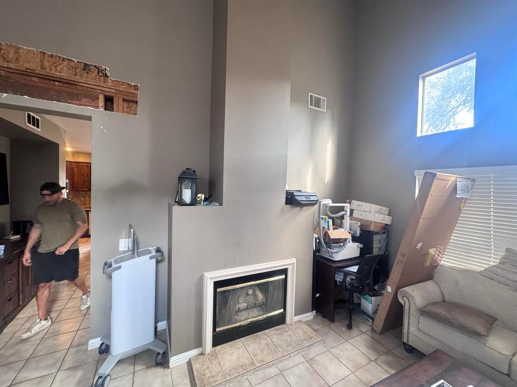 Living room with a fireplace, couch, stair area, and a person walking near the doorway.