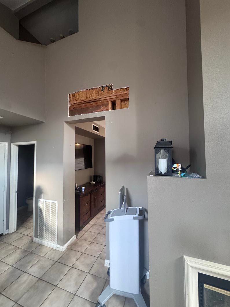 Small room with tiled floor, high gray walls, doorway to kitchen, and a water dispenser near the wall