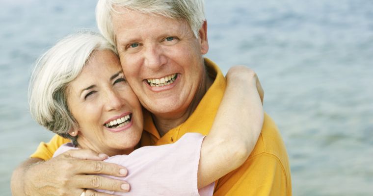 How Long Does the Dental Implant Process Take with Modern Dentistry of New England A mature couple embraces and smiles after his dental implant process with Modern Dentistry of New England
