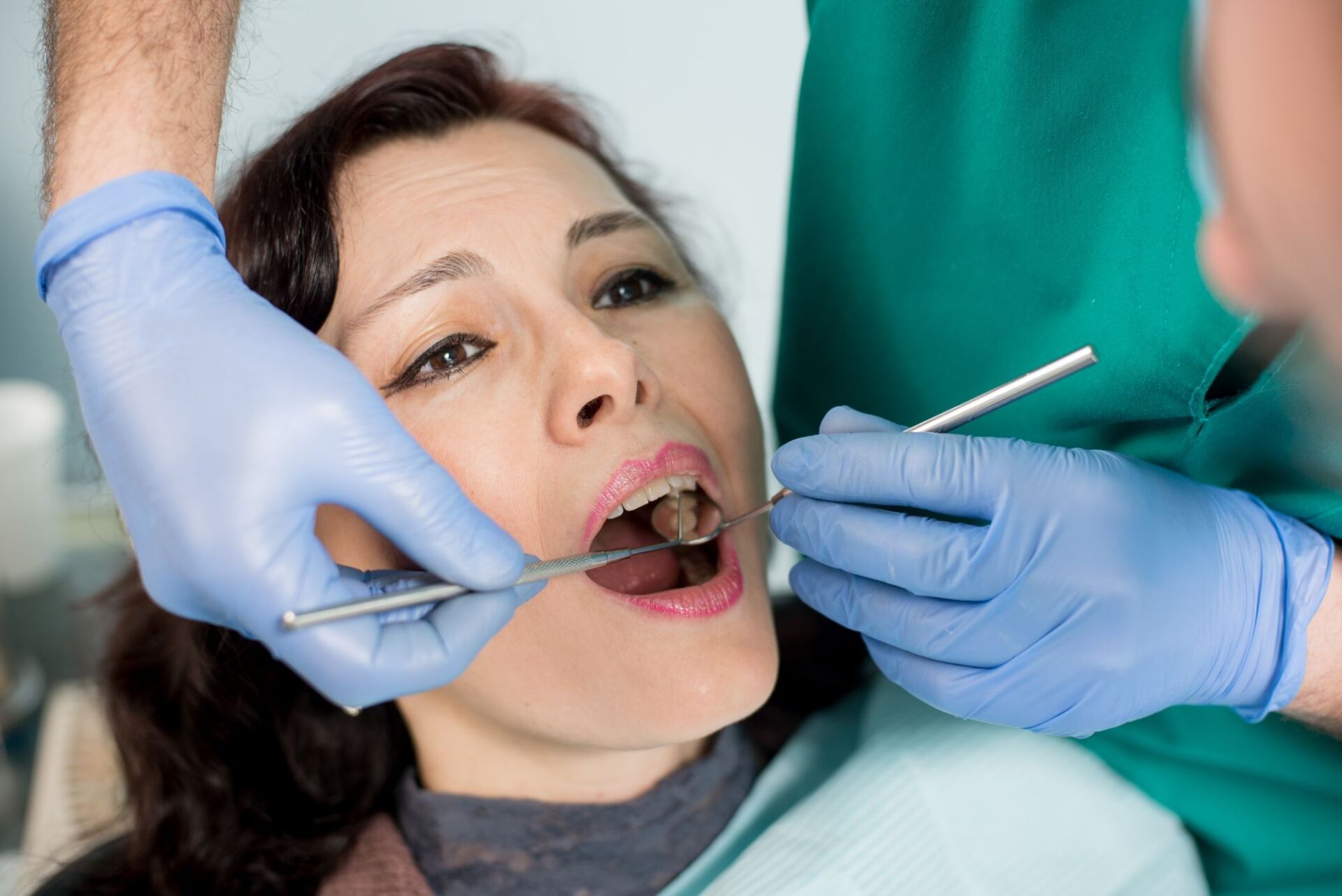A woman is having her teeth examined by a dentist.