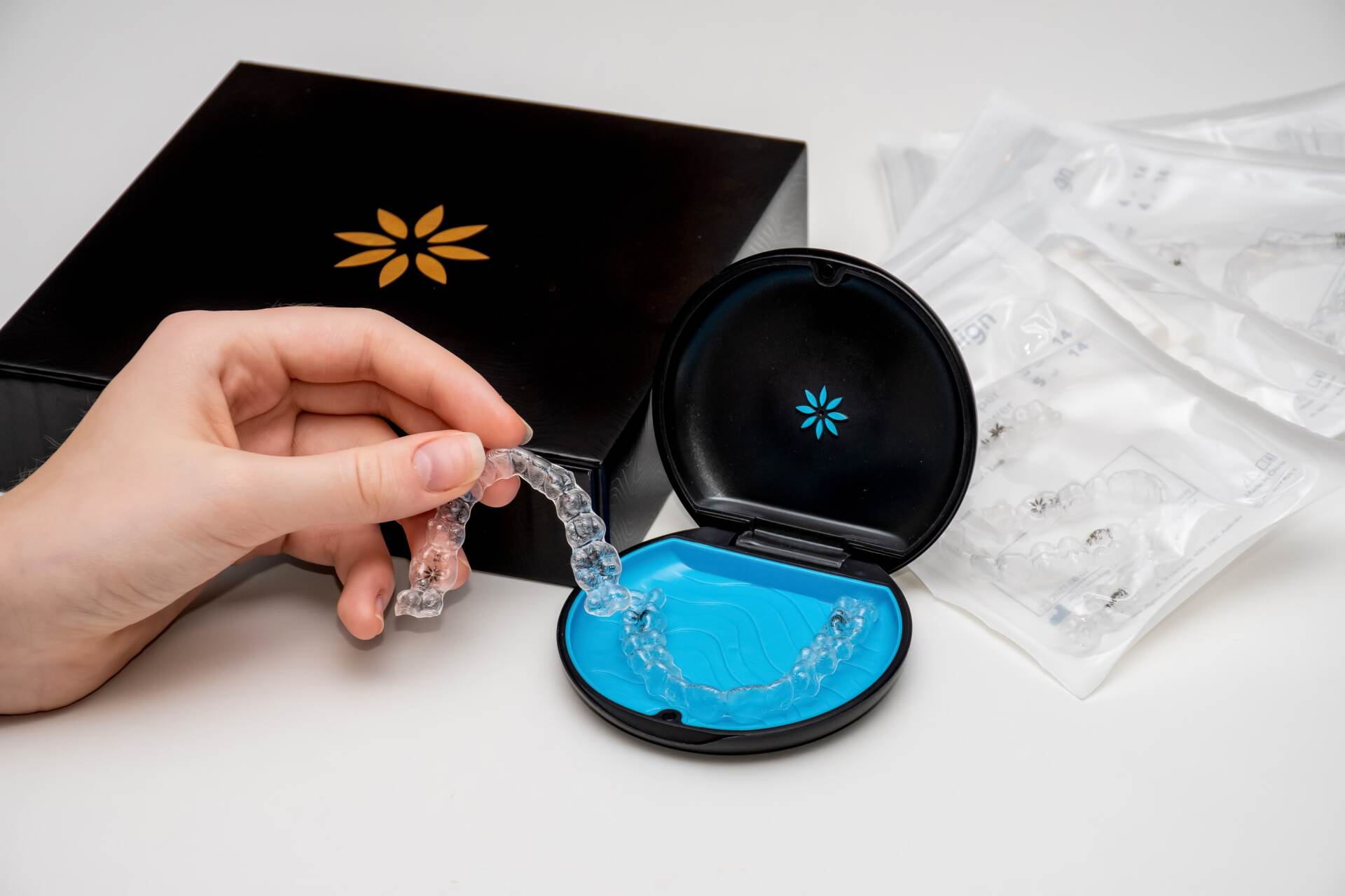 A person is holding a clear retainer in their hand in front of a box.