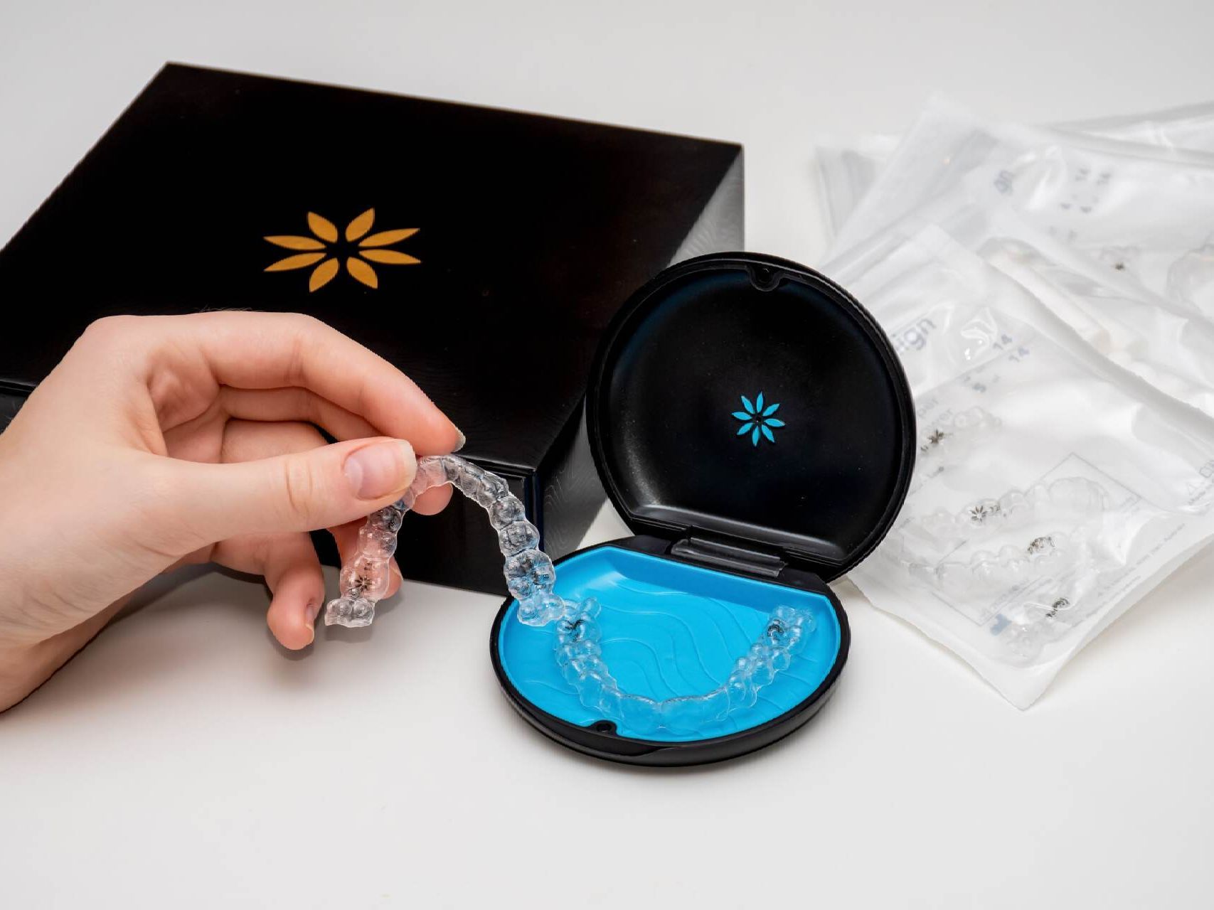 A person is holding a clear retainer in front of a box.