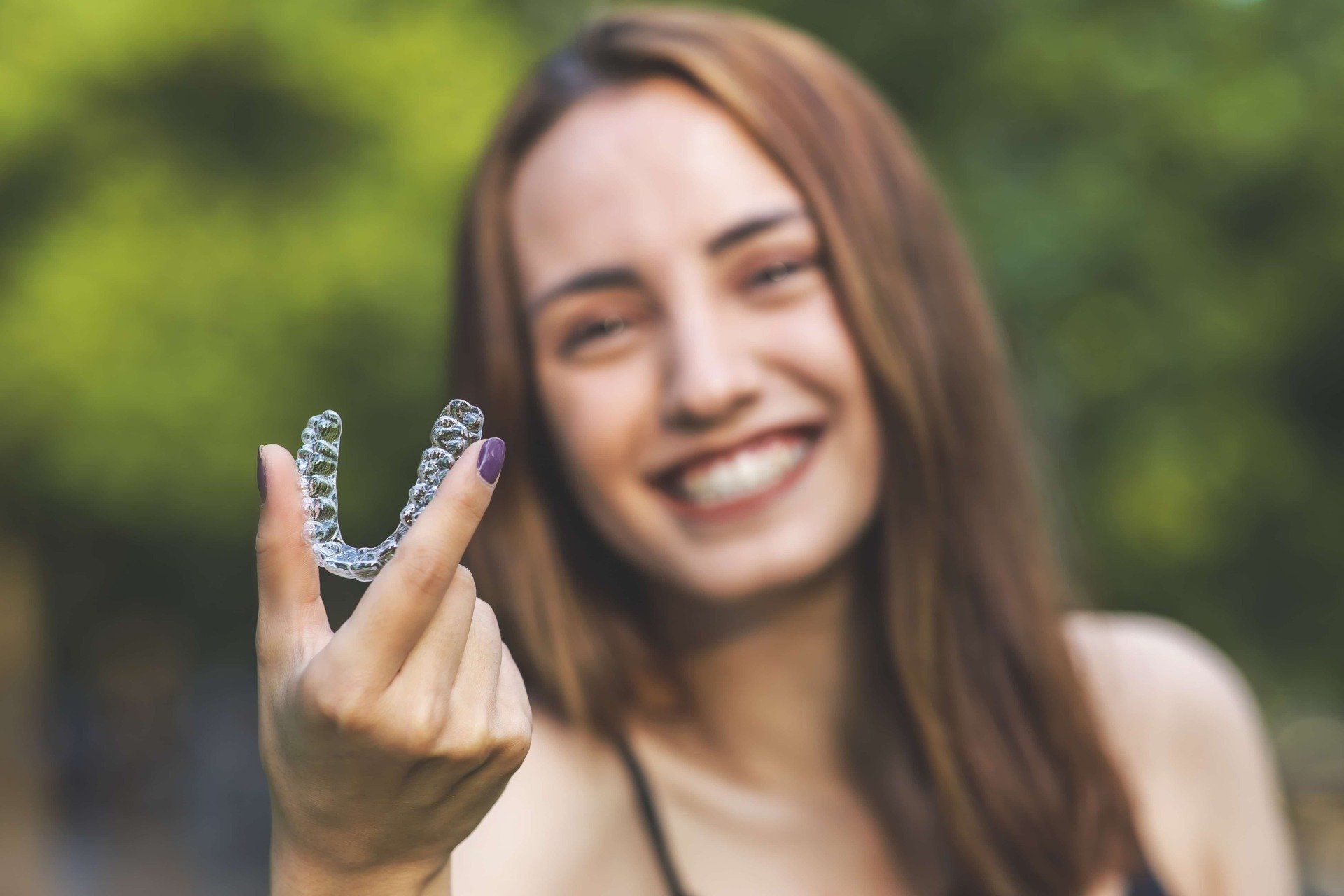 A woman is holding a clear brace on her finger.