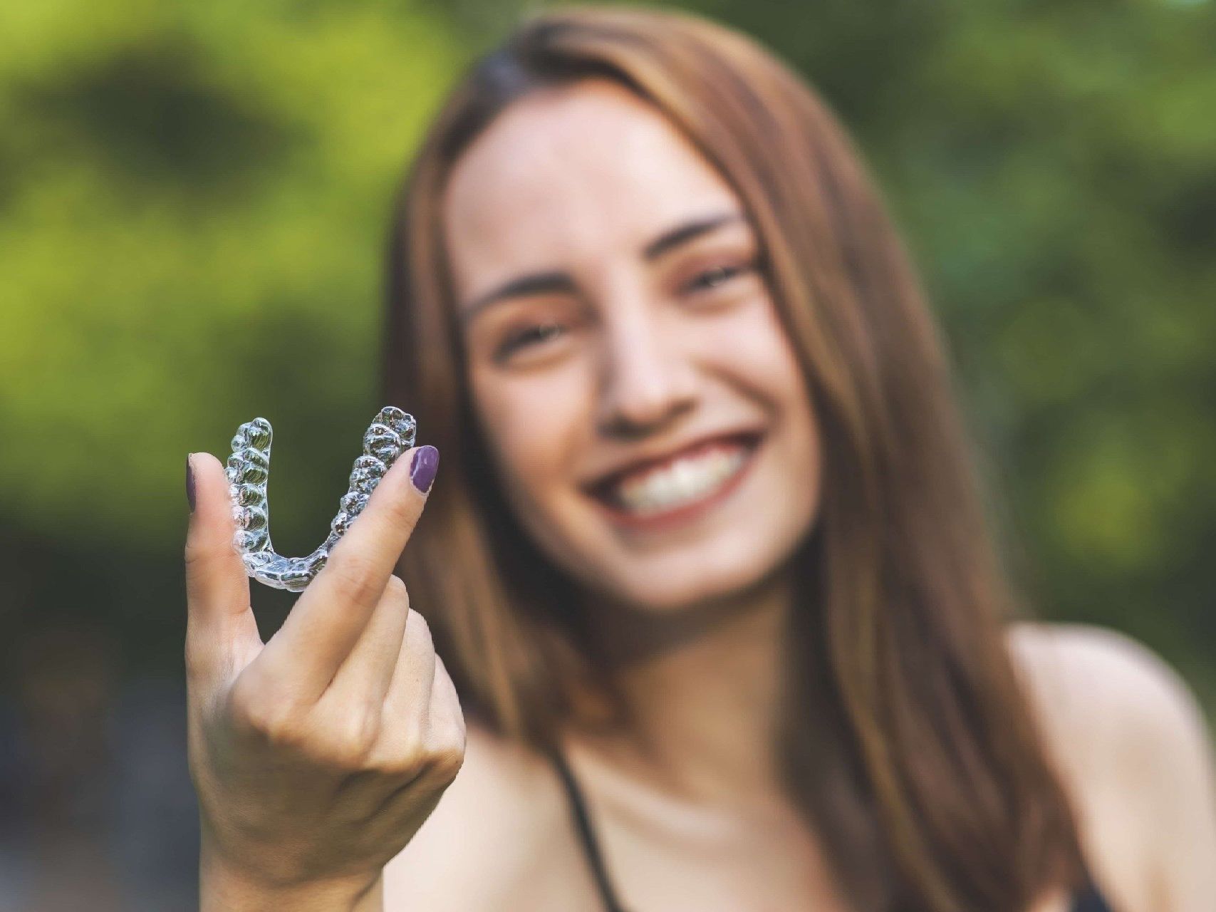 A woman is holding a clear brace on her finger.