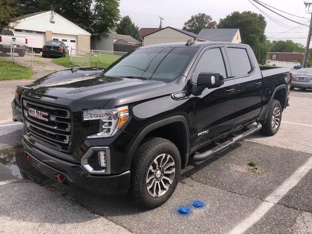 Black GMC pickup truck parked in a lot on a cloudy day