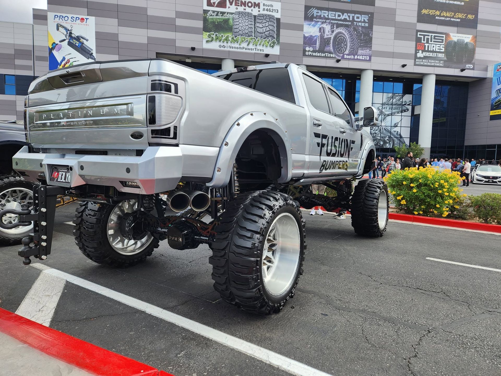 White lifted pickup truck with oversized wheels parked at an outdoor event