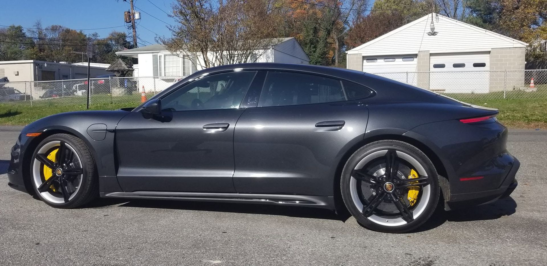 Black sports sedan parked outdoors in a suburban neighborhood, side view.