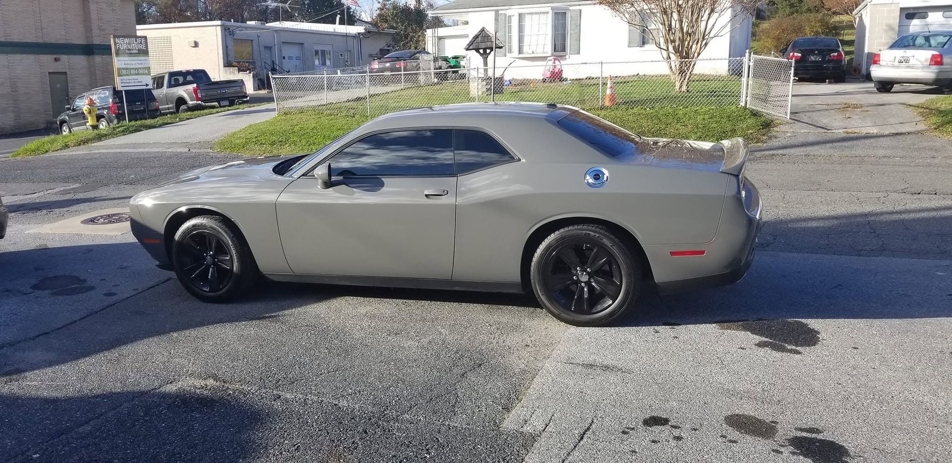 Silver classic muscle car parked on a gravel lot in front of buildings