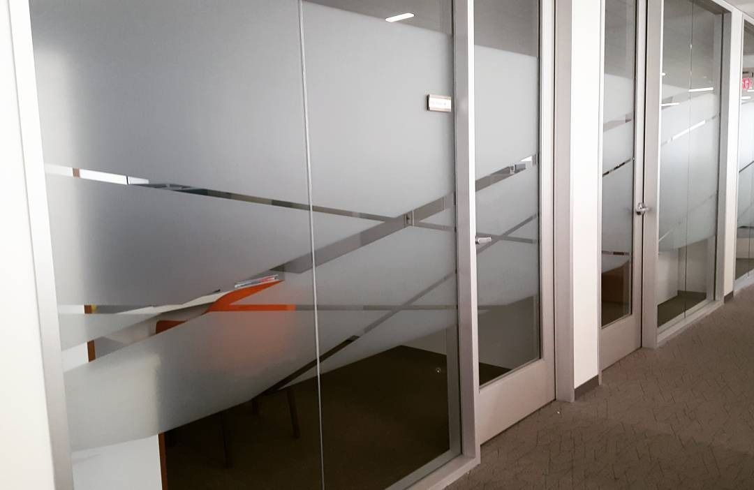 Glass office doors with frosted diagonal stripes and a glimpse of a red chair inside