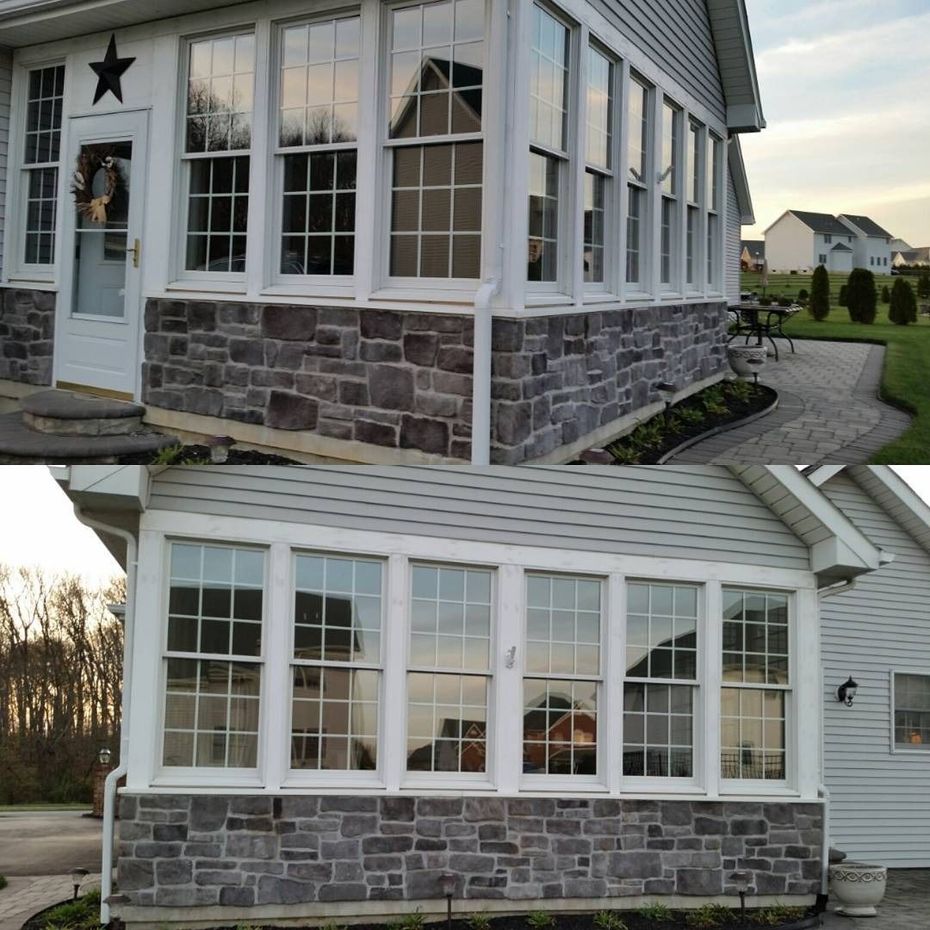 Stone and white house exterior with large windows, star on the door, and a sloped roof under construction