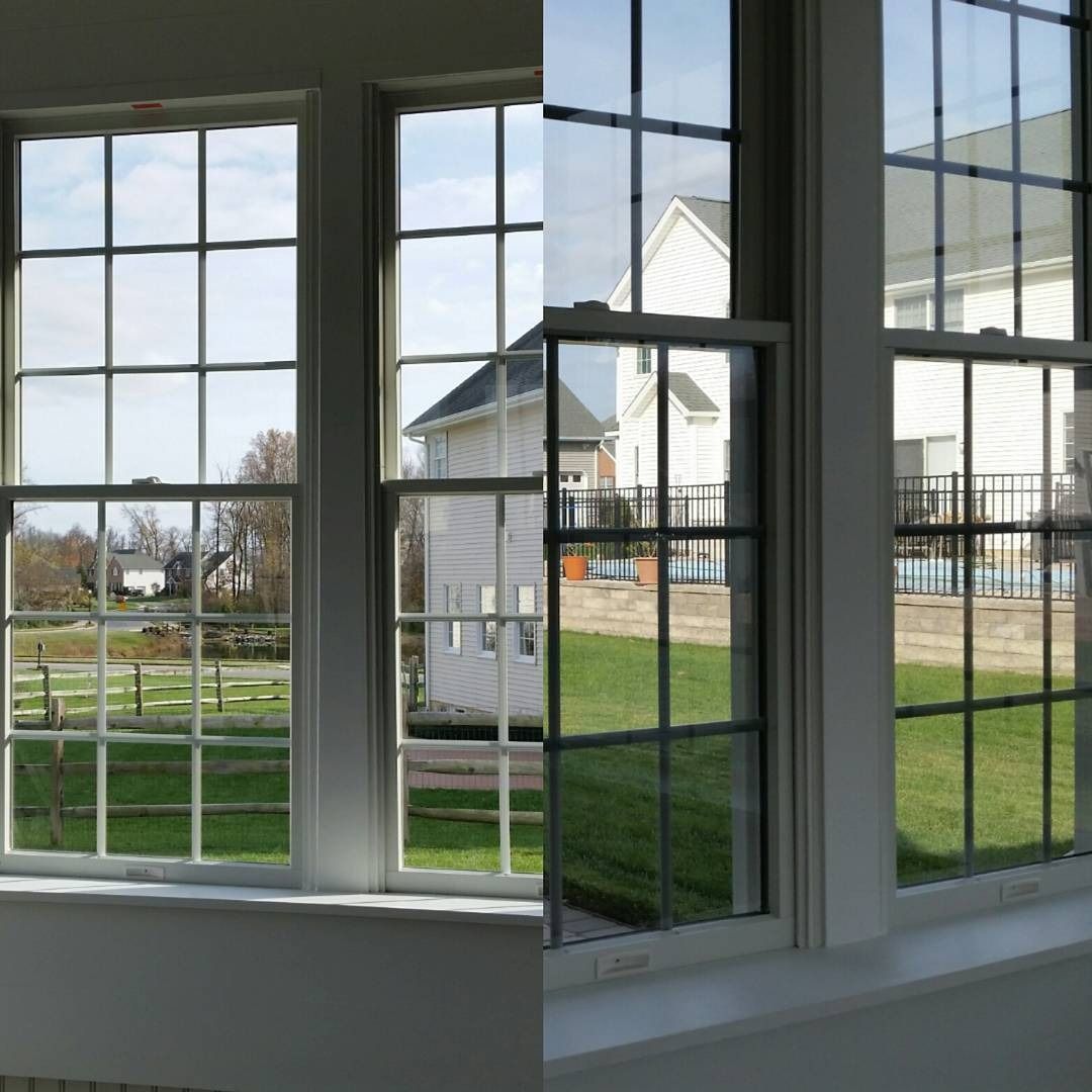 View through white window panes to a grassy yard and a white house on a sunny day