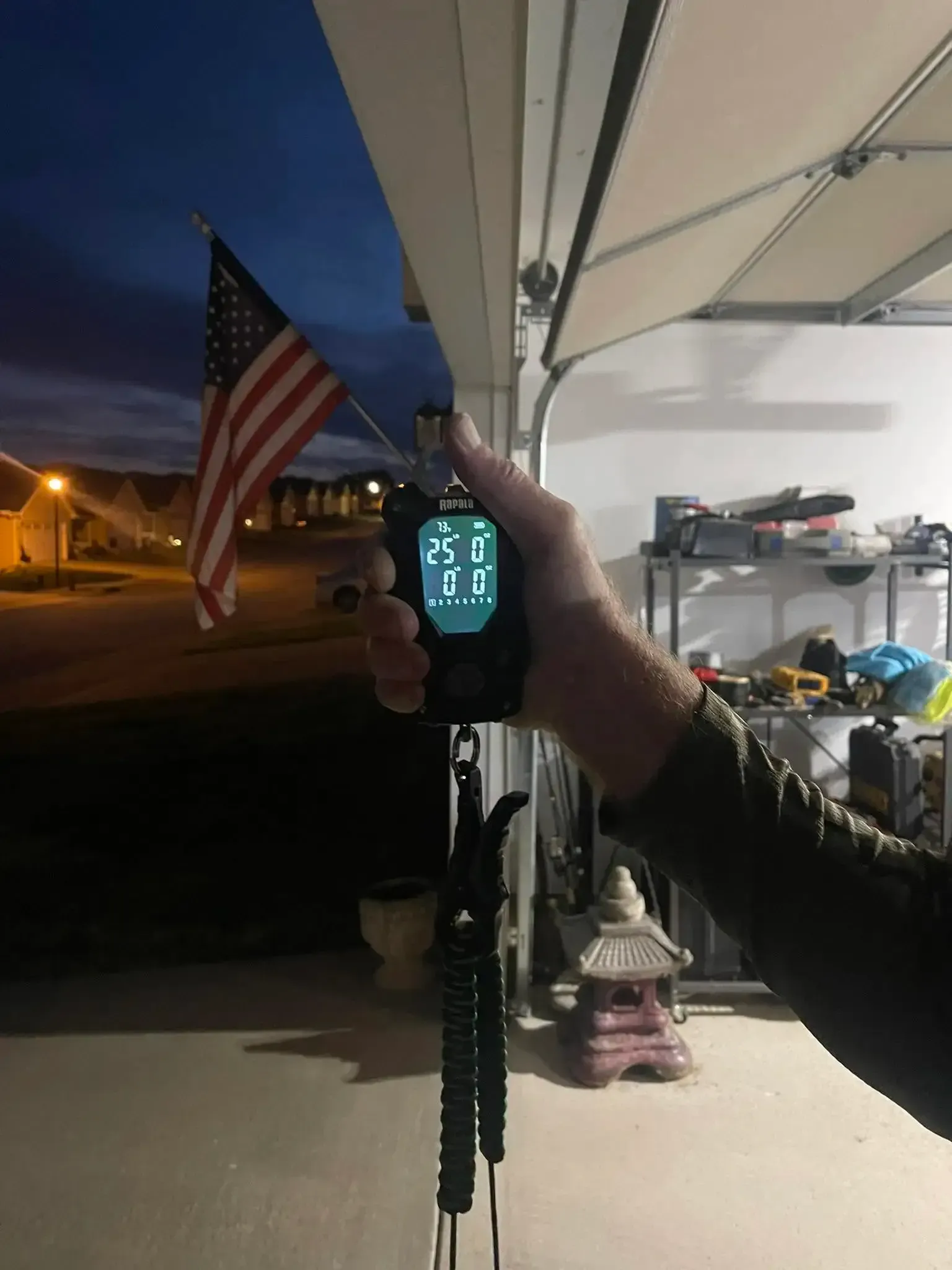 Handheld radio glowing in a covered porch at dusk, with an American flag in the background.