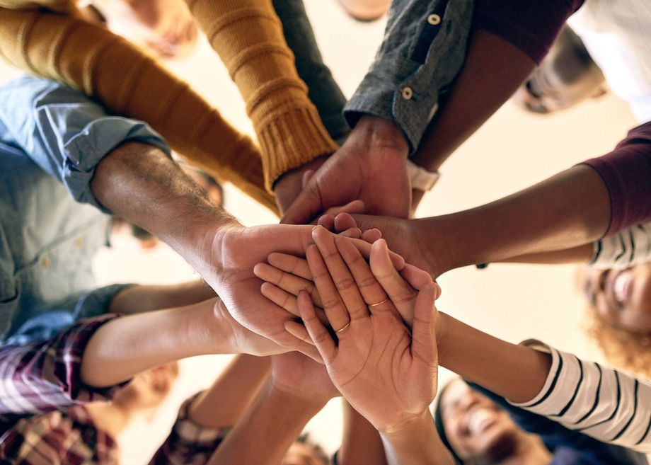 A group of people are putting their hands together in a circle.