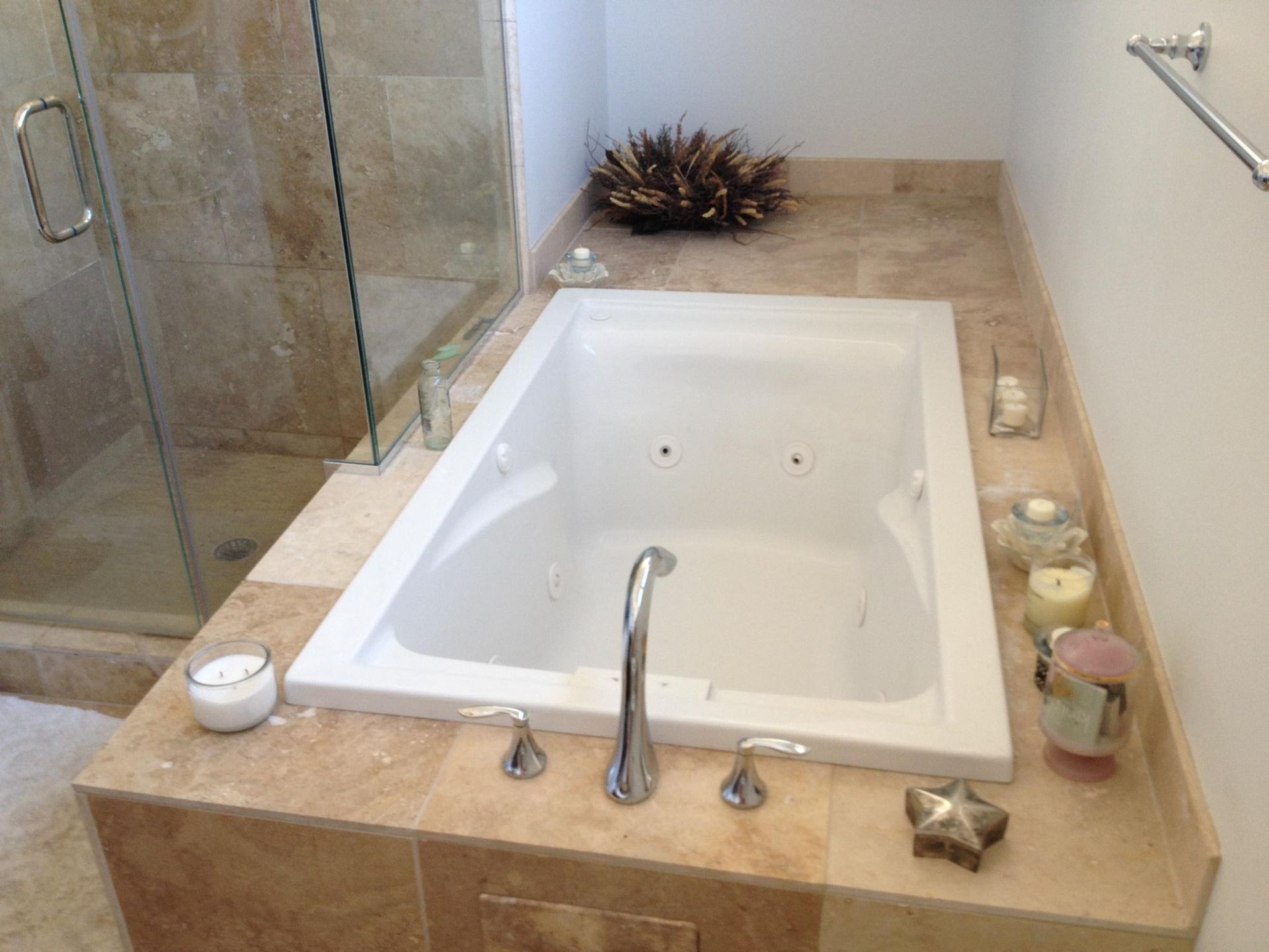 Bathroom with a white corner bathtub, beige tile surround, and glass shower enclosure