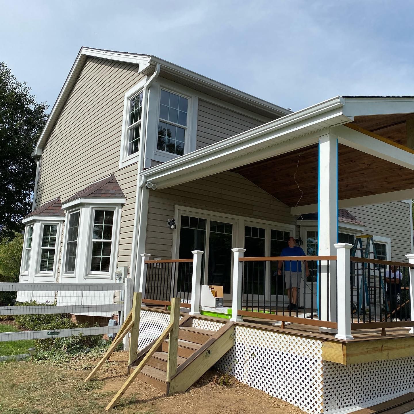 Two-story house with a covered porch and ramp access, viewed from the yard