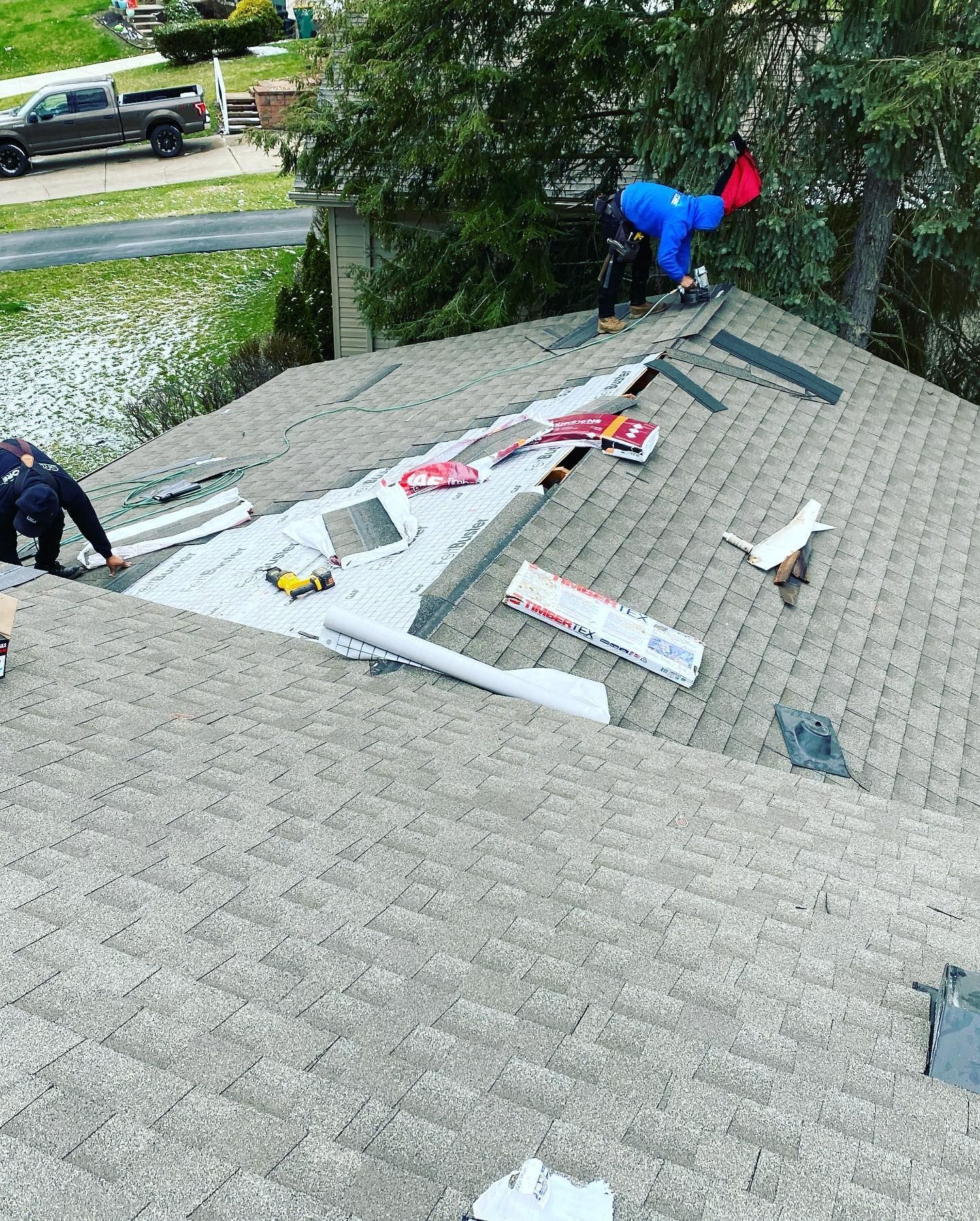 Workers placing roofing materials on a sloped roof during repairs