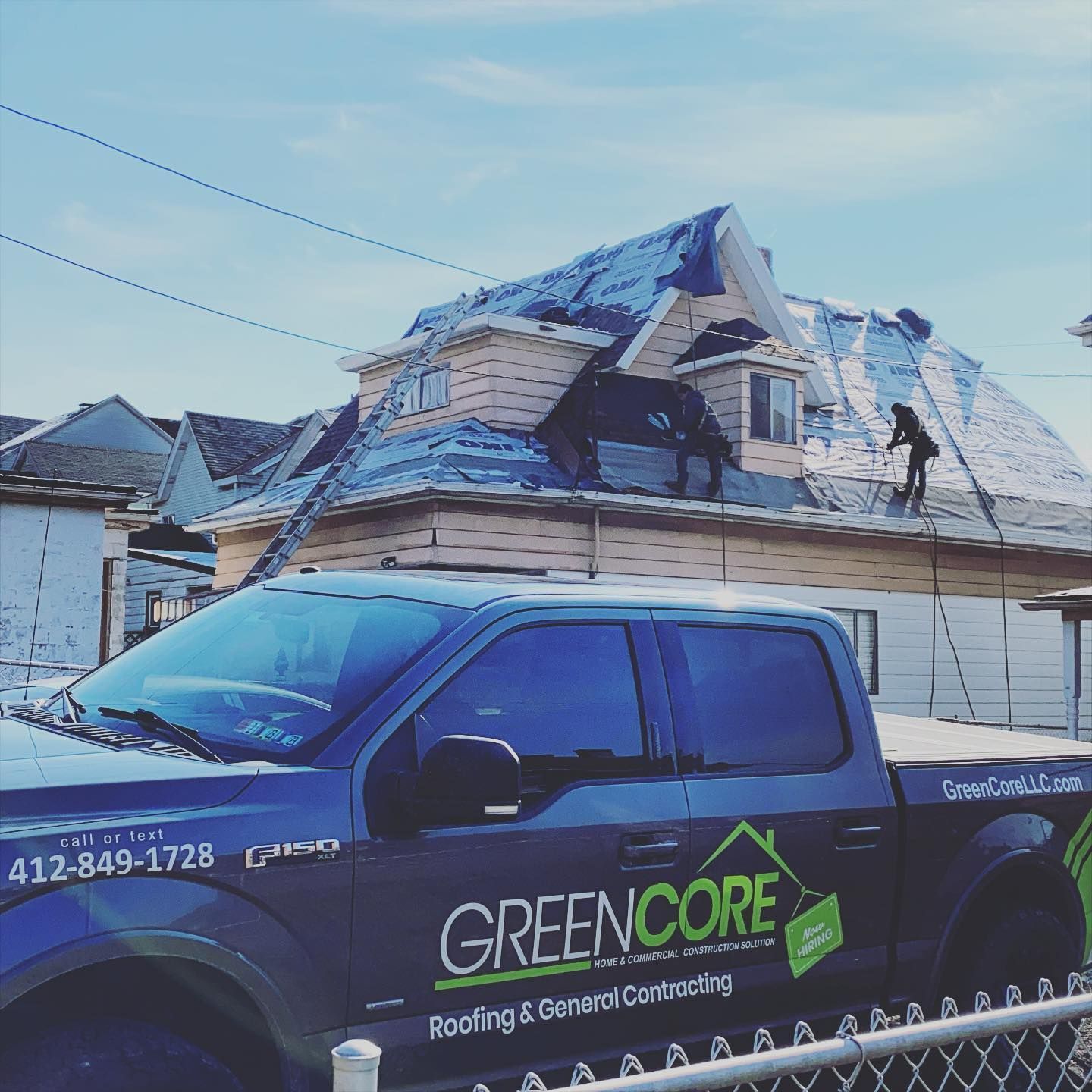 Green Core Roofing truck parked beside a snow-covered house with a damaged roof under repair