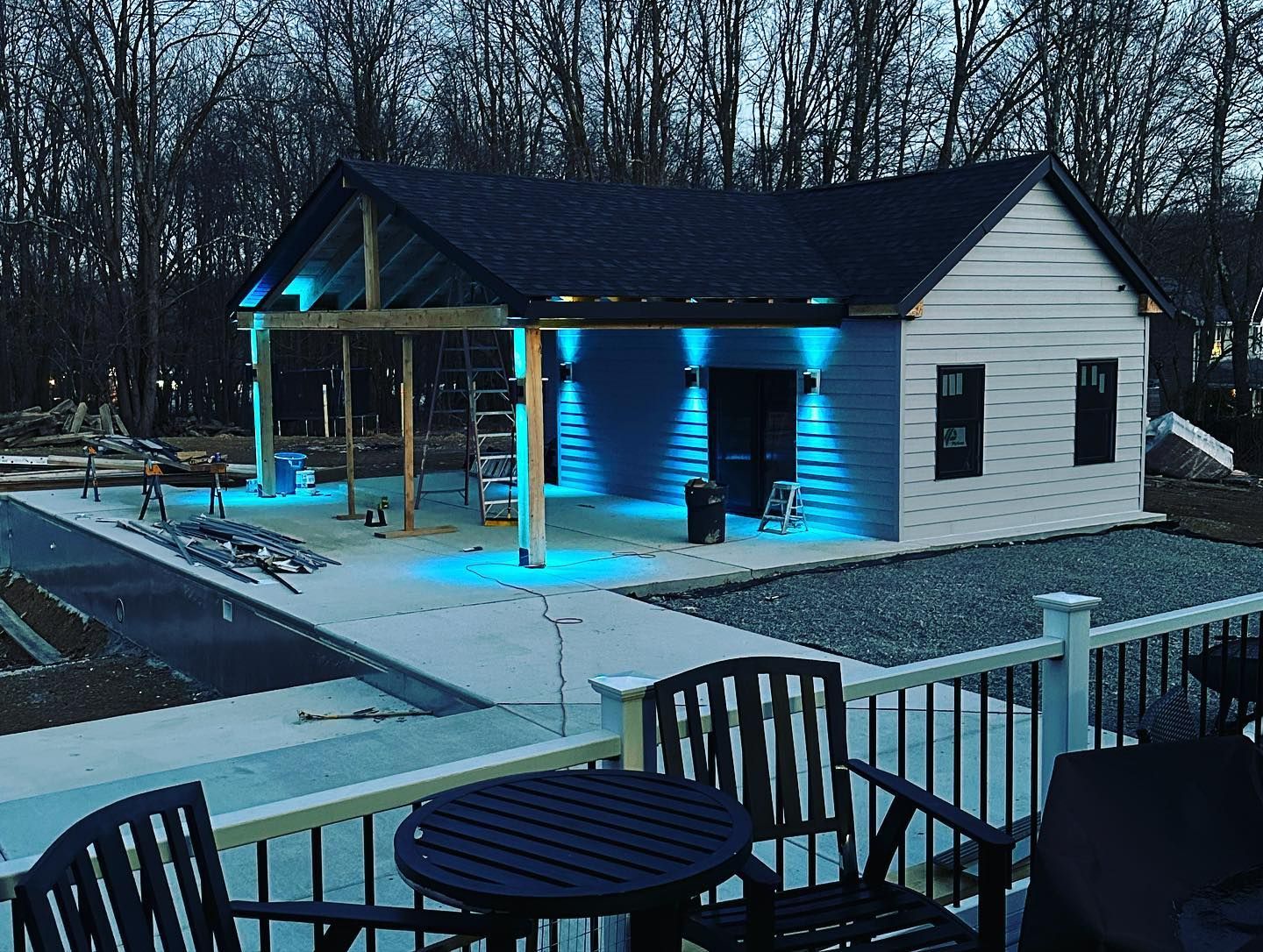 Backyard patio with a lit gazebo and blue accent lights at dusk, viewed from a deck