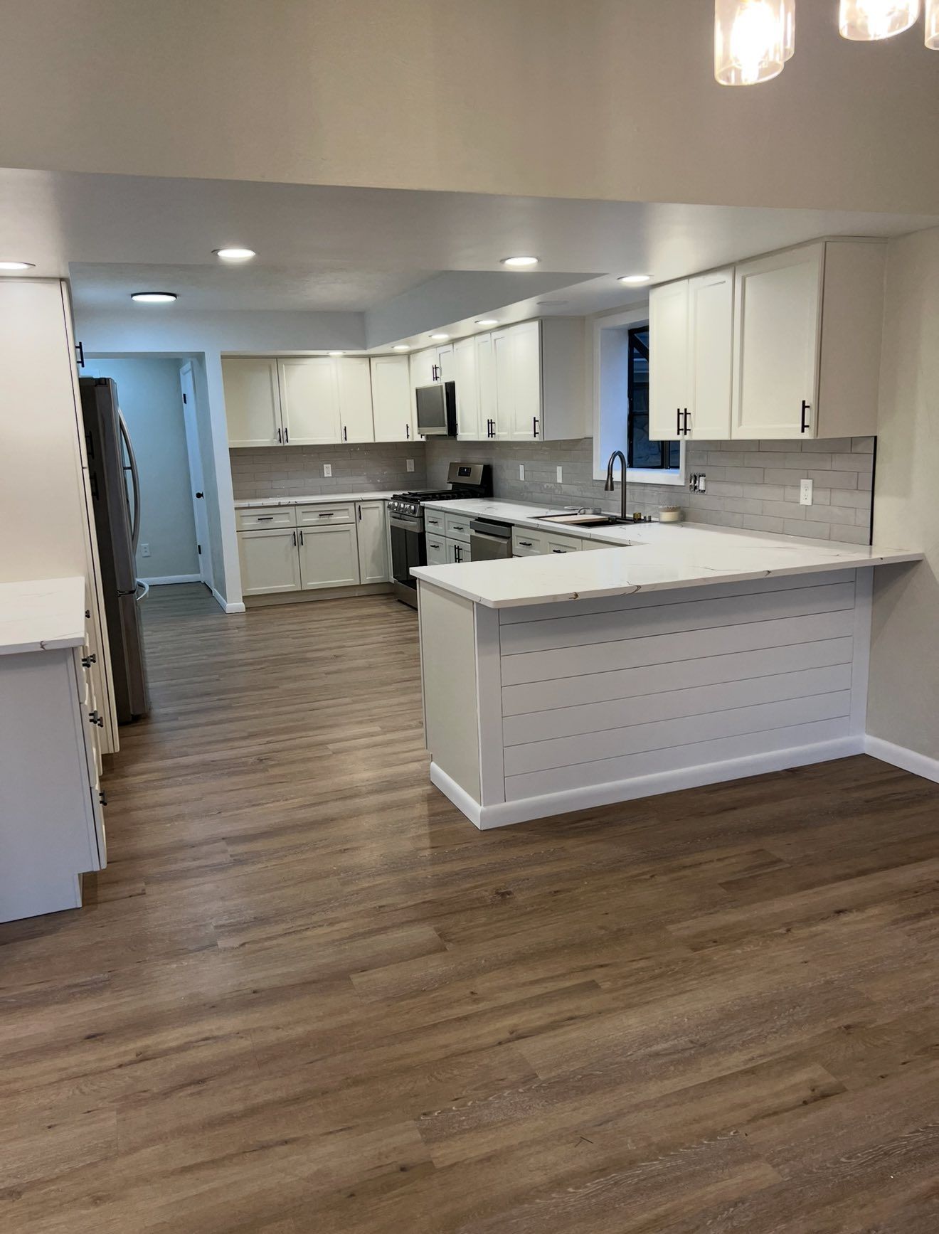 Bright modern kitchen with white cabinets, island, and wood-look flooring