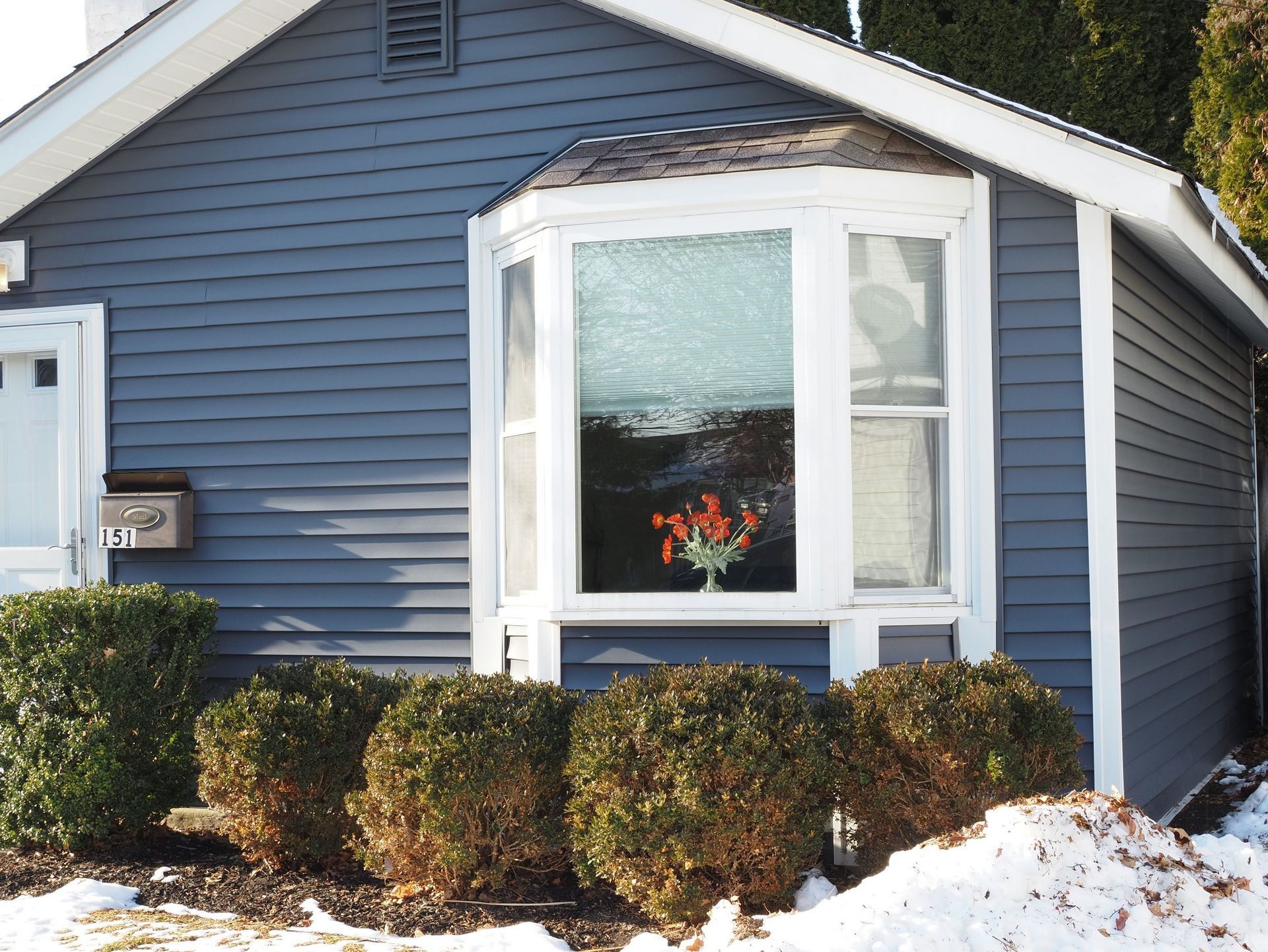 Blue house exterior with a small gabled entry roof and round vent