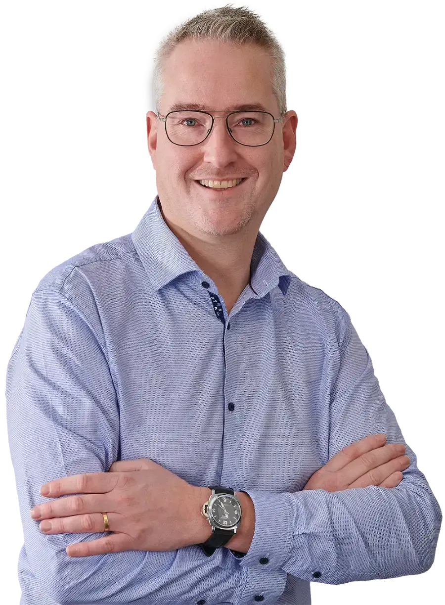 Een man met een bril en een horloge staat met zijn armen over elkaar.