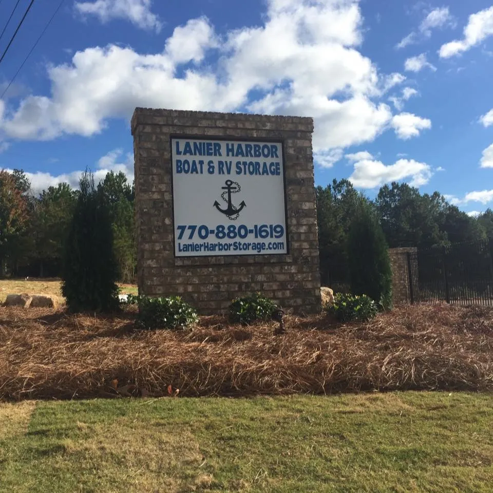 Sign for Lanier Harbor Boat & RV Storage; brick structure with text, anchor graphic, and phone number against a blue sky.