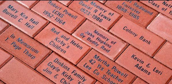 Close-up of commemorative bricks with names and dates inscribed on them.