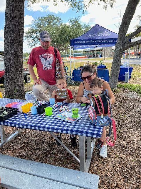 A family is sitting at a picnic table in a park.