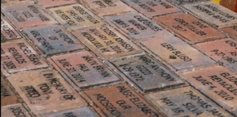 Bricks with inscribed names, dates, and tributes. Some are red, orange, and gray.
