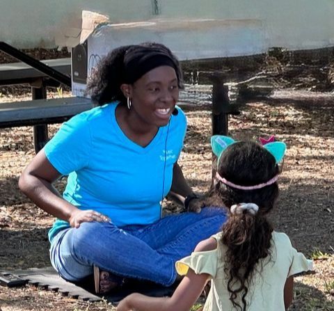 A woman in a blue shirt sits next to a little girl