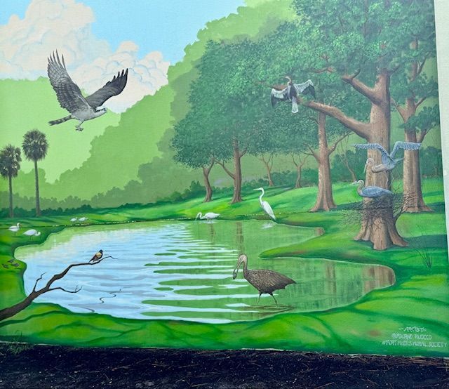 Mural of a wetland scene with birds, trees, and water; an eagle flies above. Green, blue, and brown tones.