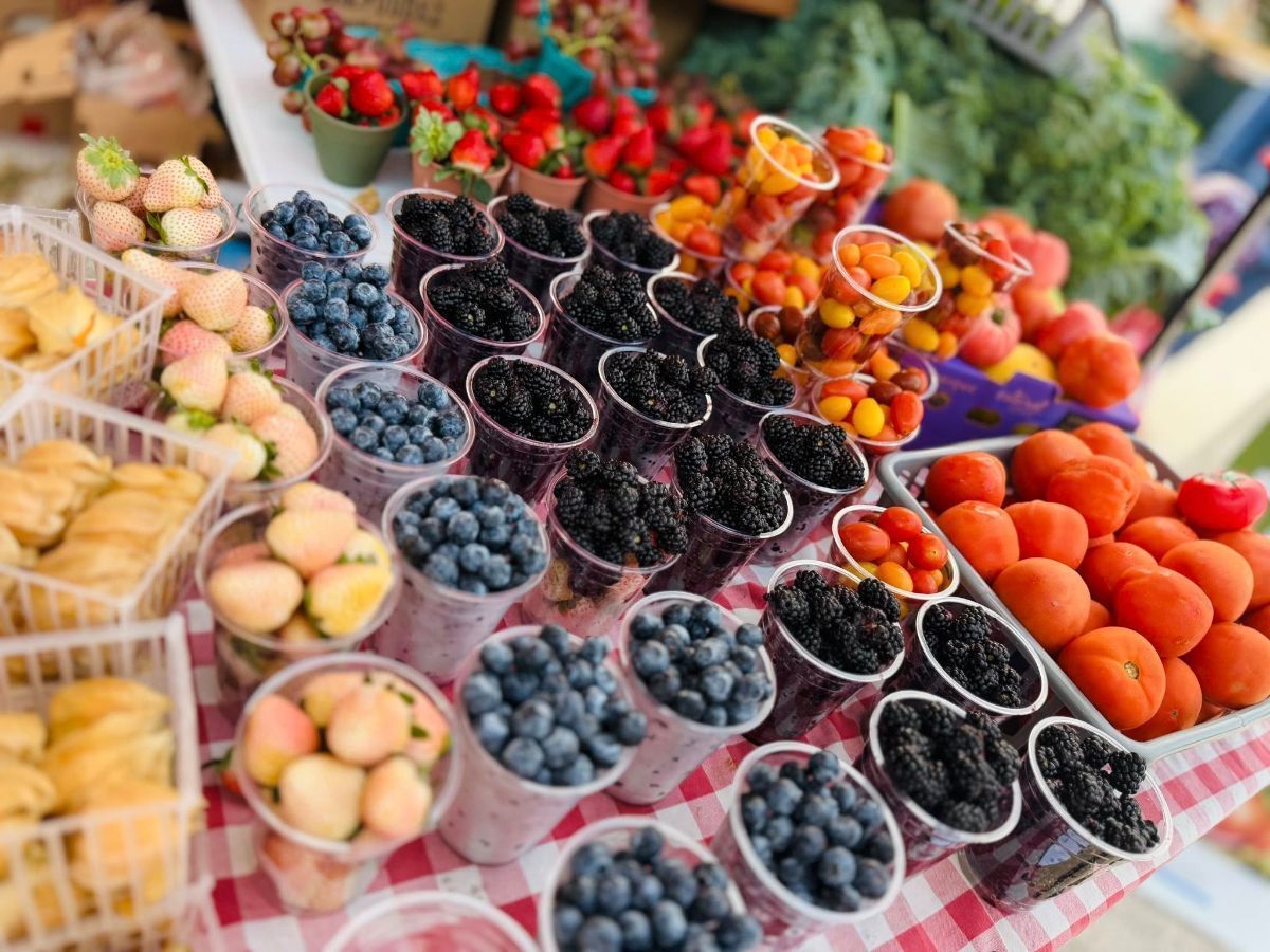 Fresh berries and fruit for sale at a farmers market; blueberries, strawberries, apricots, peaches.