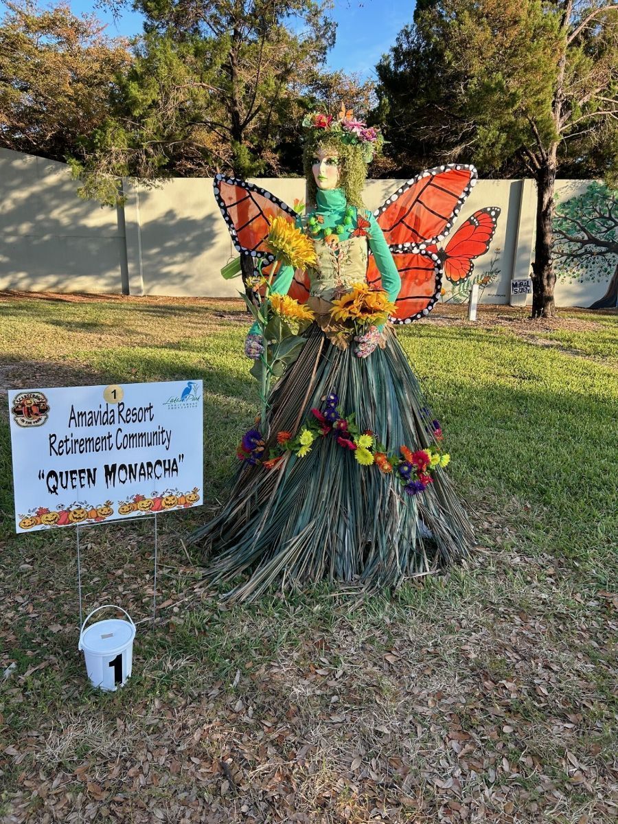 Fairy sculpture made of natural materials with butterfly wings, flowers, and a sign that says