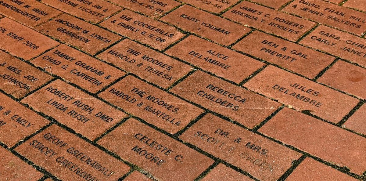 Bricks with engraved names arranged in a walkway pattern.