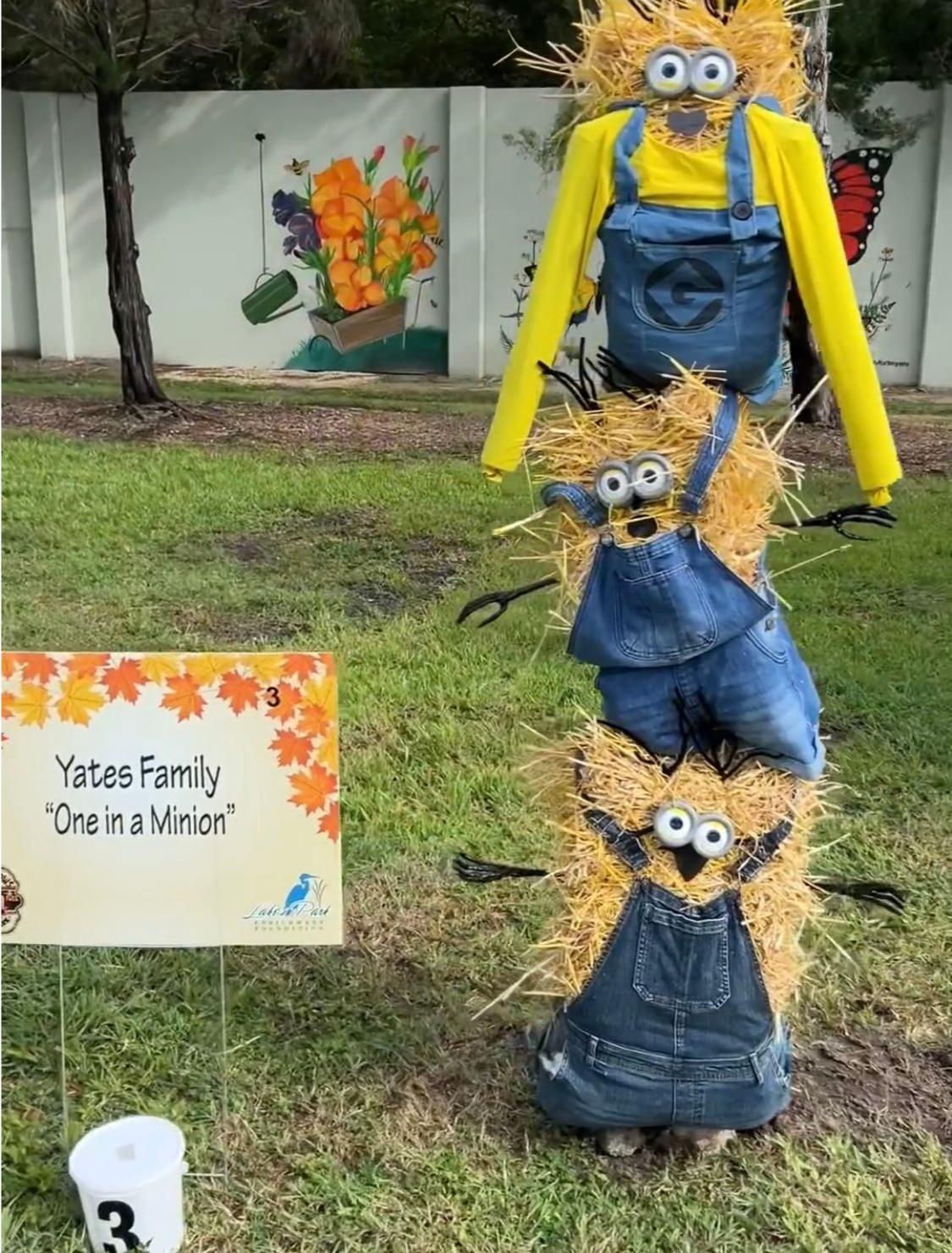 Hay bale Minion scarecrow family display. Yellow, denim, and grass setting.