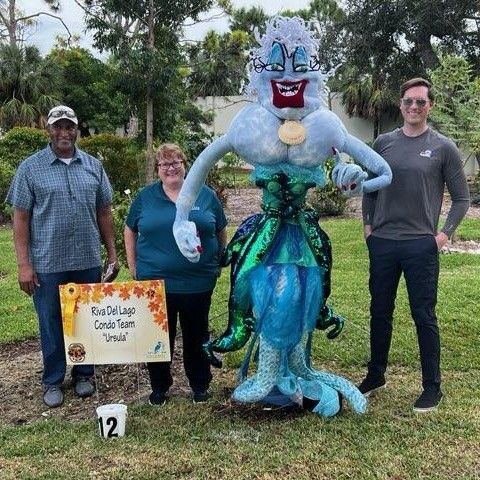 A group of people standing next to a scarecrow in a park.