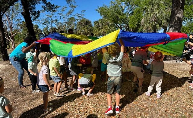 A group of children are playing with a colorful parachute.