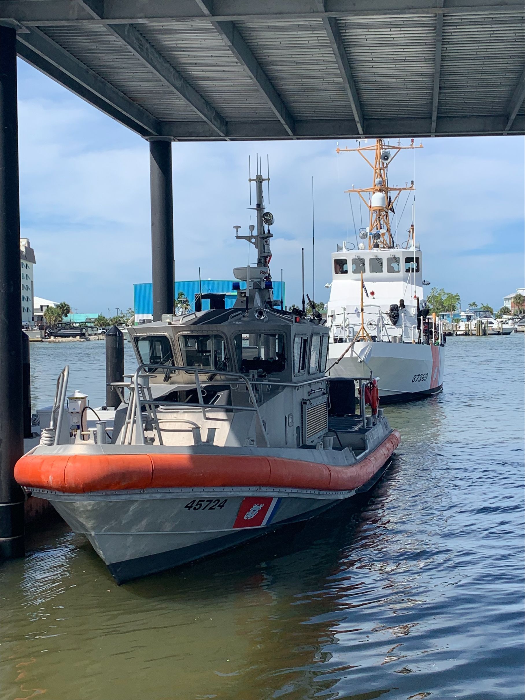 Two boats are docked under a bridge in the water.