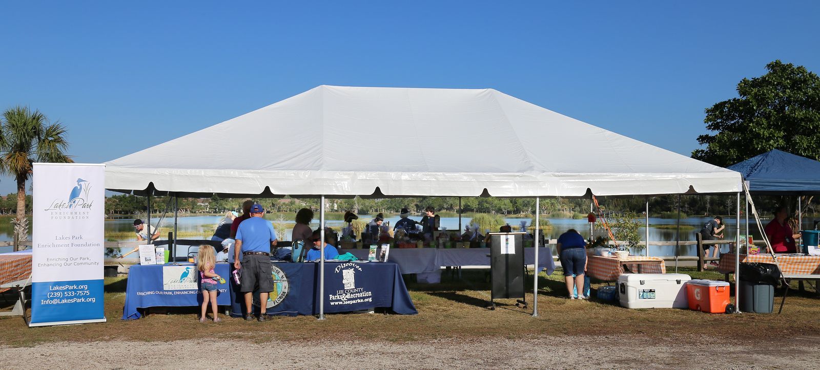 A group of people are standing under a white tent.