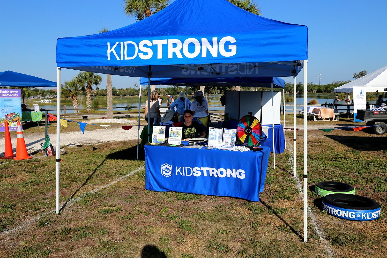A blue tent with the word kidsstrong on it is sitting in the middle of a field.