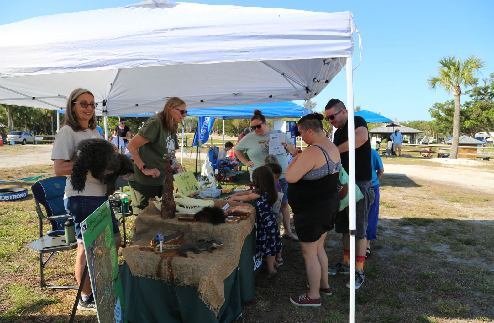 A group of people are standing around a table under a tent.