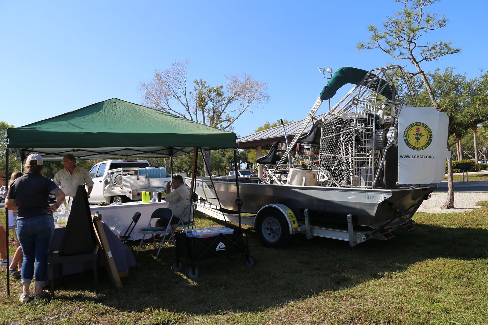 A group of people are standing in front of a boat on a trailer.