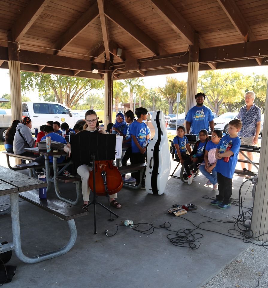 A woman playing a cello in front of a group of children