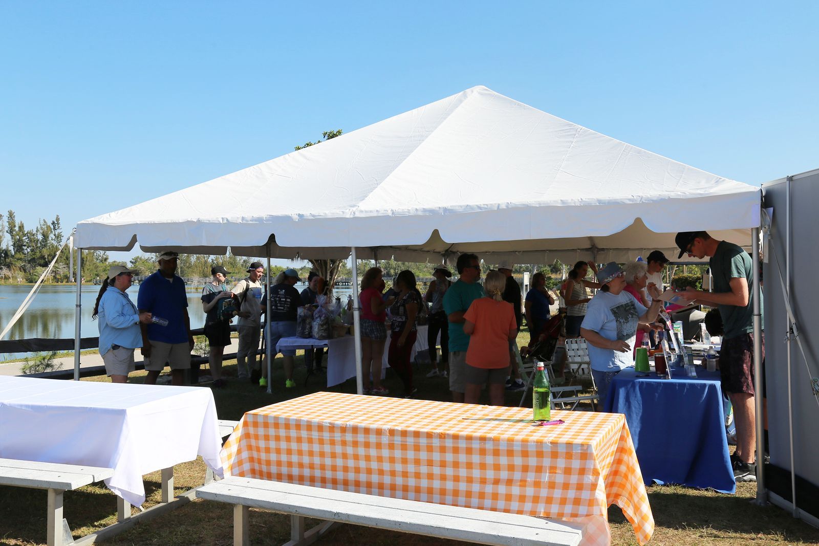 A group of people standing around tables under a tent