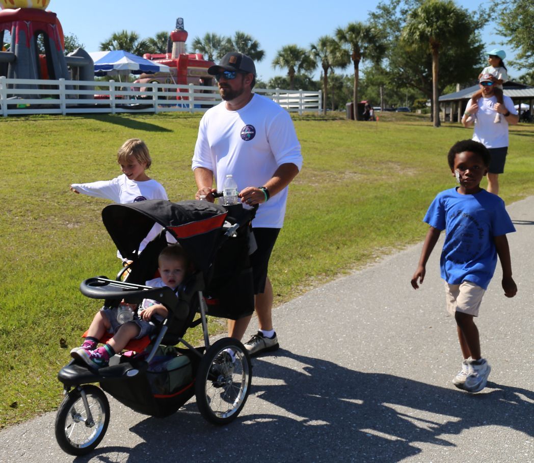 A man pushes a stroller with two children in it