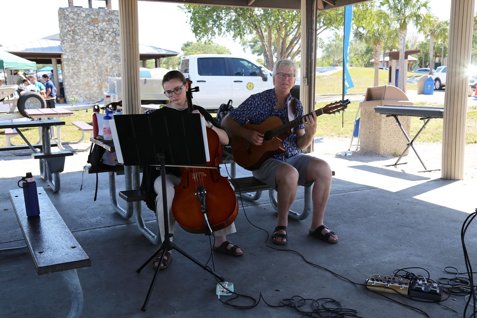 A man is playing a guitar and a woman is playing a cello