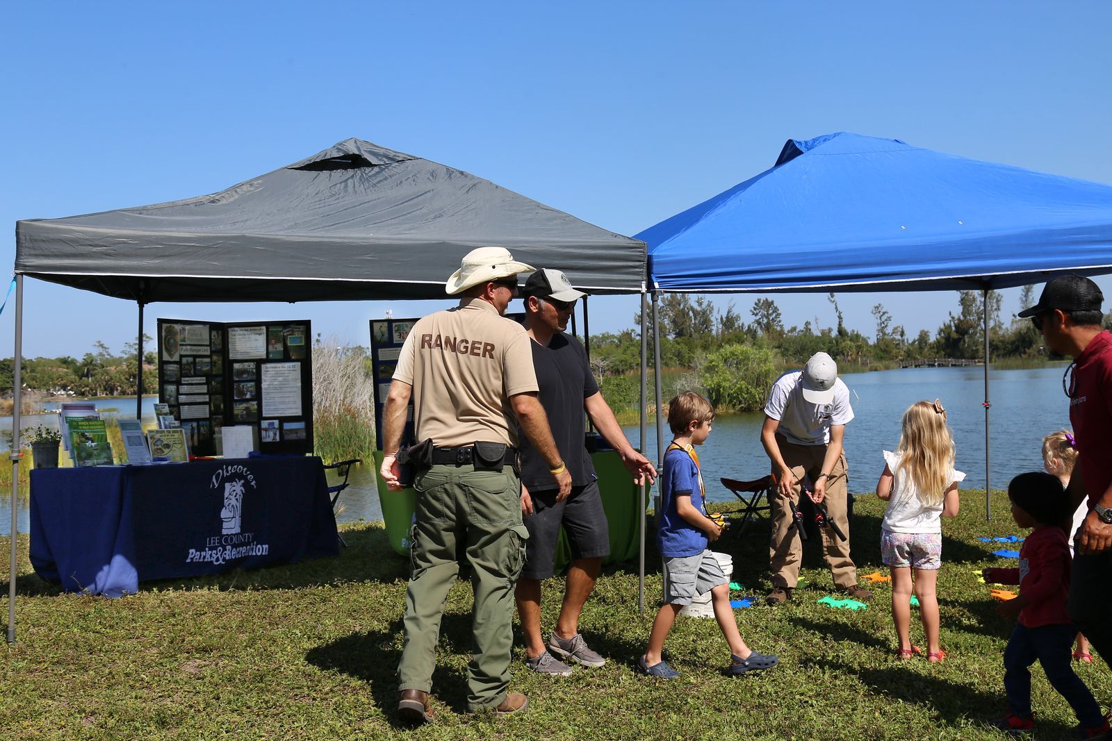 A group of people are standing under tents in a field.