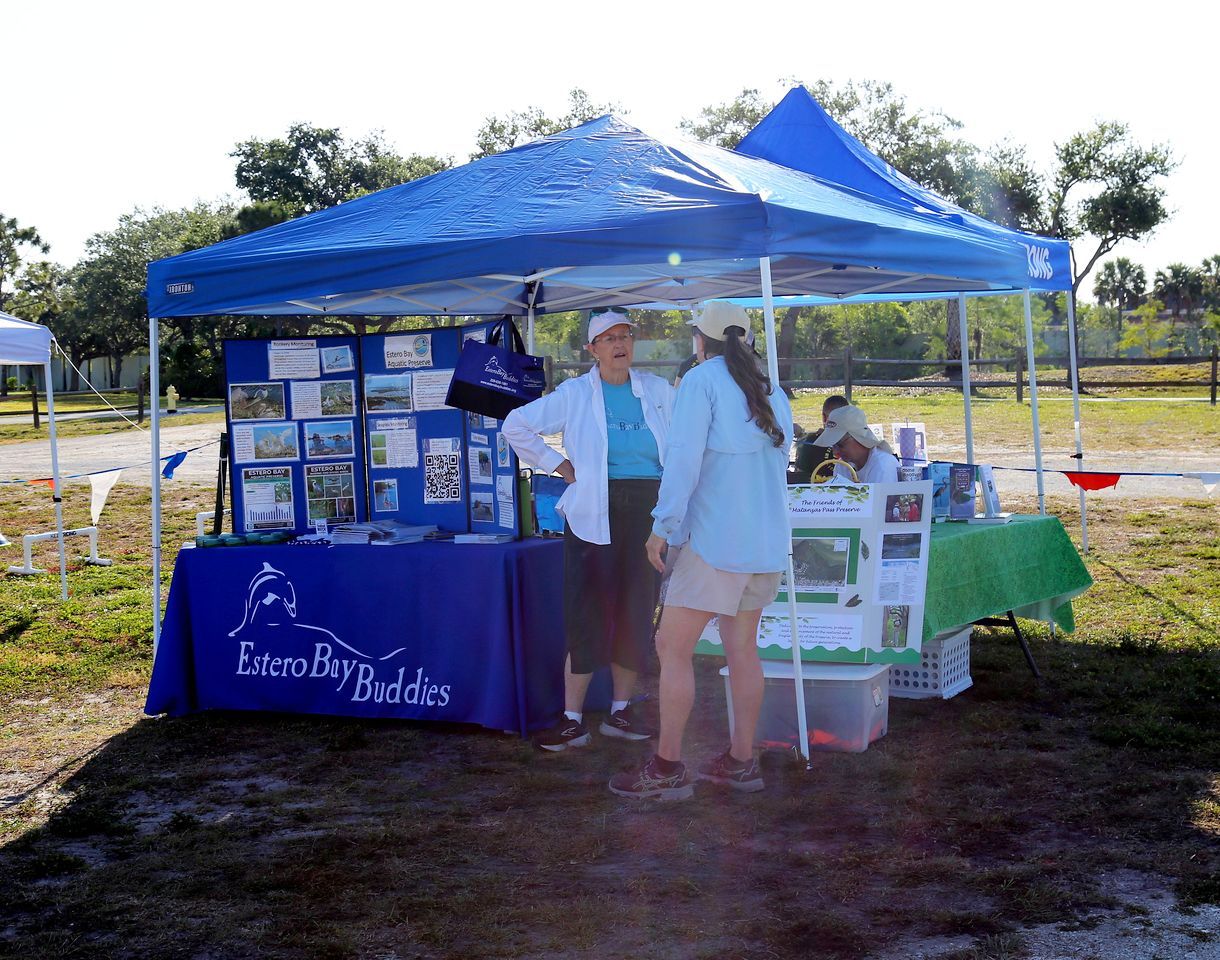 A woman stands in front of a blue tent that says eccentric buddies